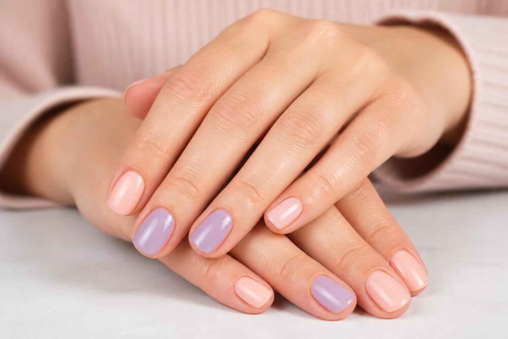 Dłonie z pastelowym różowym i fioletowym manicure hybrydowym na jasnym tle